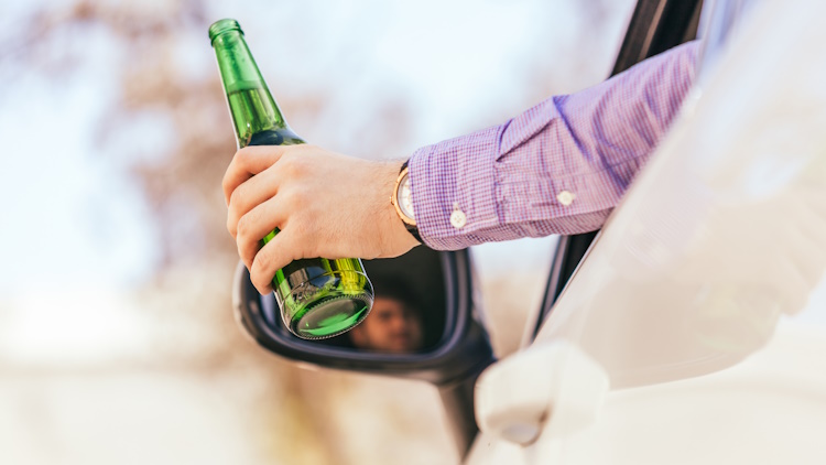 man drinking alcohol while driving the car